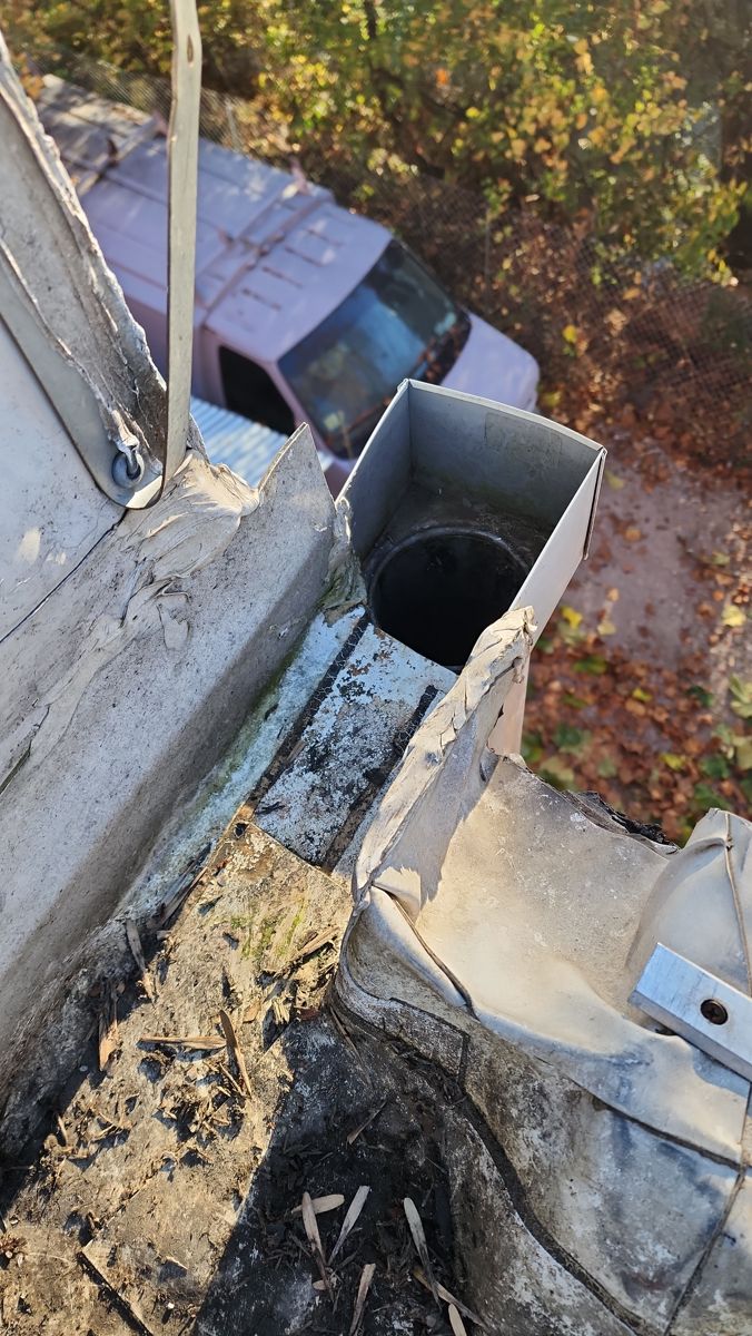 Torn and worn membrane around a drain outlet on a commercial flat roof