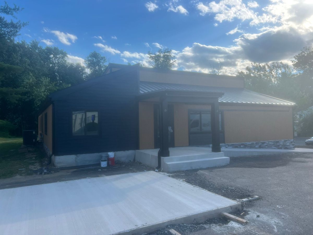 Finished building with dark lap siding, wood-tone vertical siding and a standing-seam metal roof