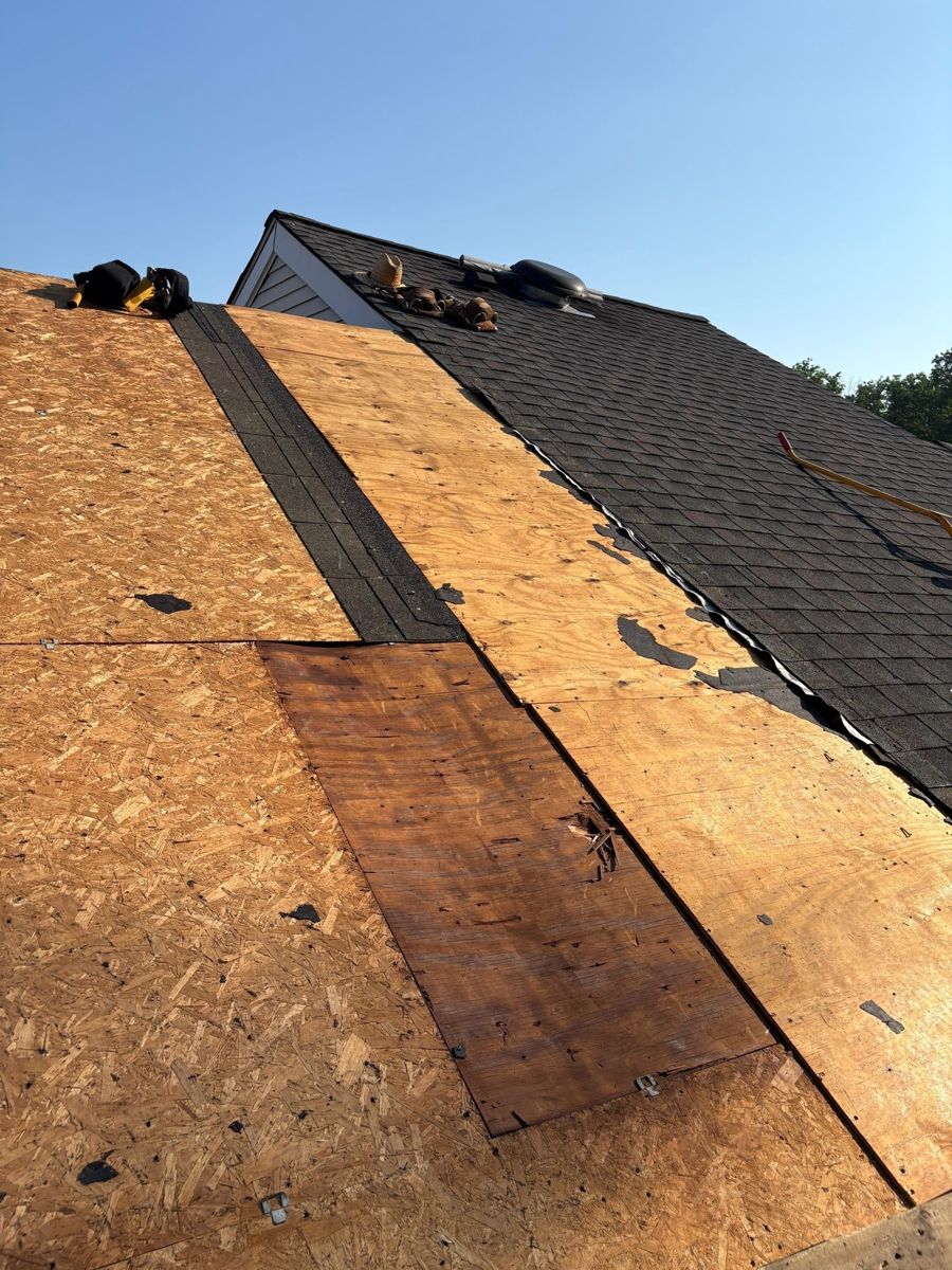 Old dark shingles half torn off, with new and existing roof decking exposed on a Doylestown roof