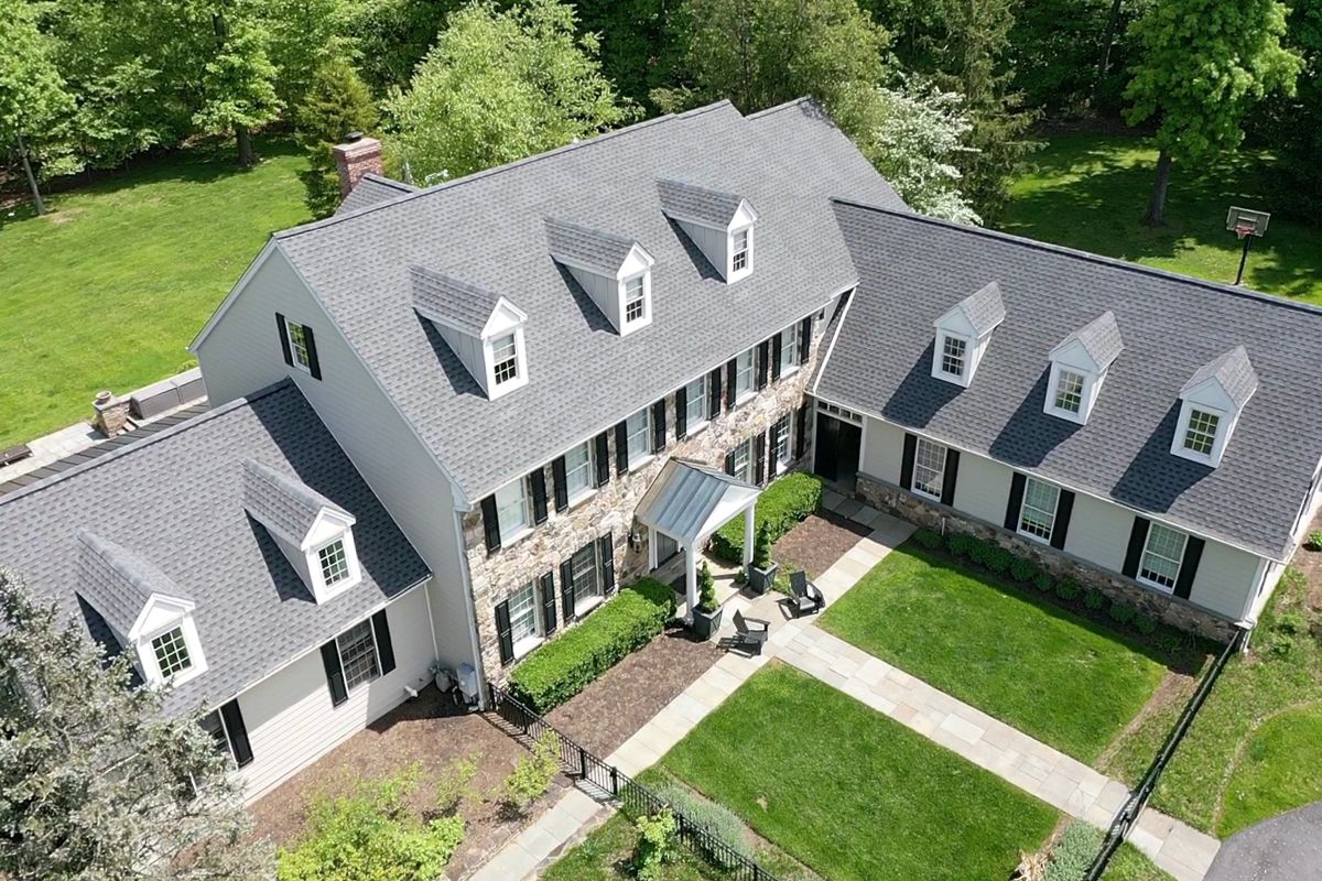 Aerial view of the same Doylestown colonial with a uniform new gray shingle roof and dormers