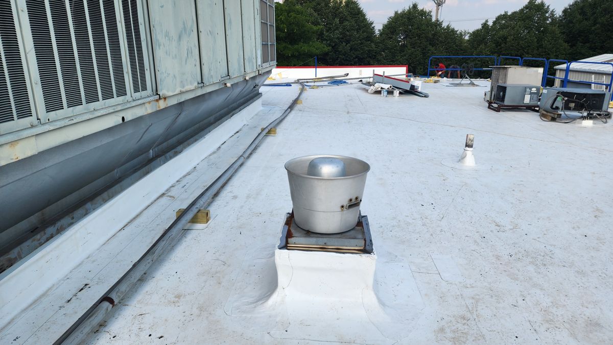 Finished white flat roof with the exhaust fan re-flashed on its curb
