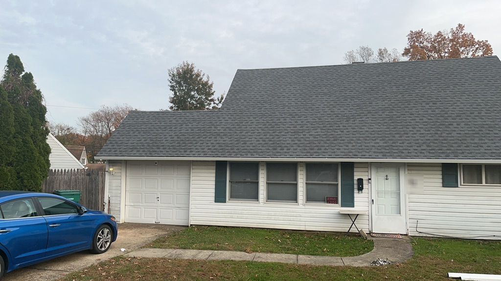 New dark gray architectural shingle roof on a classic Levittown, PA home