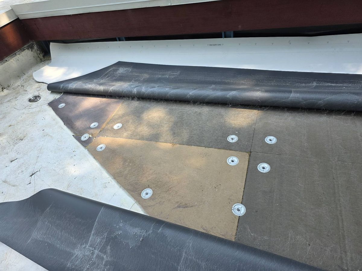 New roof layers fastened down on a flat roof in Penn Valley, PA with membrane being rolled out
