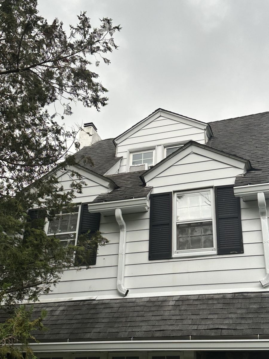 Worn gray shingle roof and dormers on a white colonial in Penn Wynne, PA before replacement