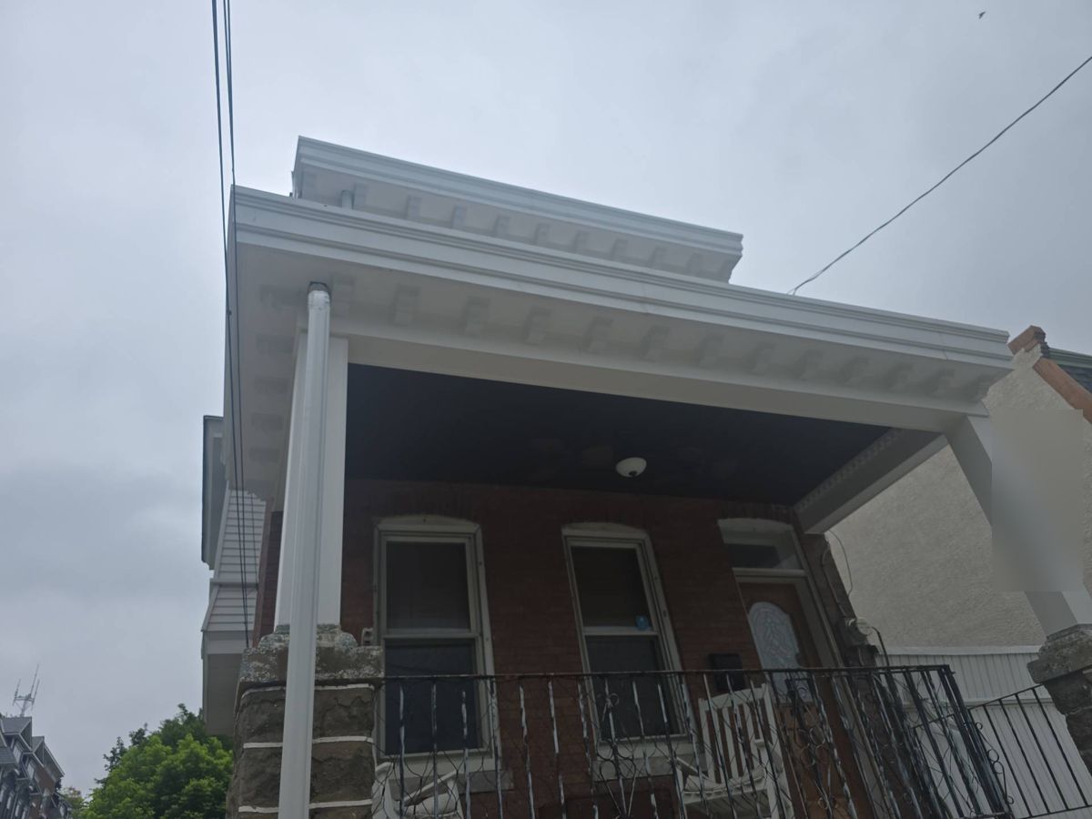 Finished white porch roof trim and cornice on a brick rowhome in Manayunk