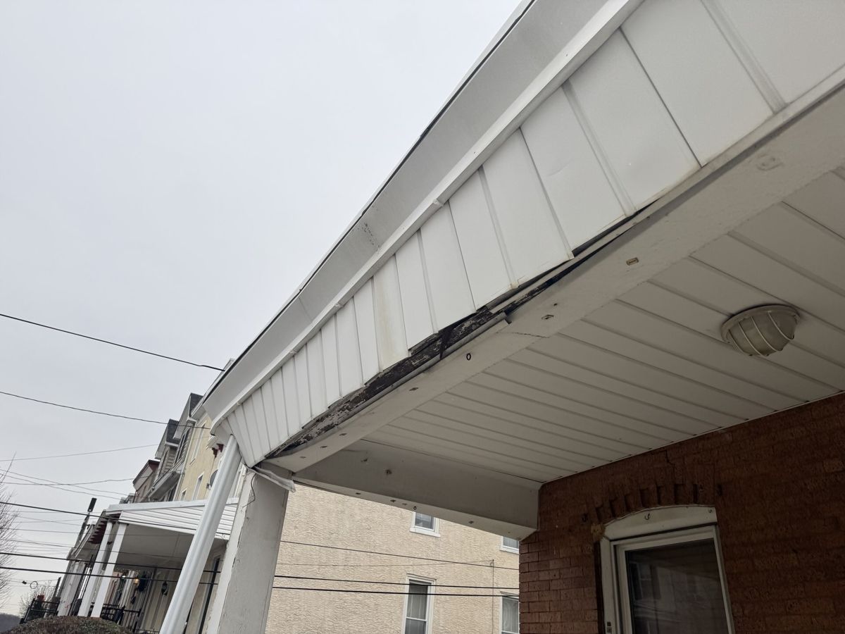 Sagging, damaged fascia and soffit on a rowhome porch roof in Manayunk