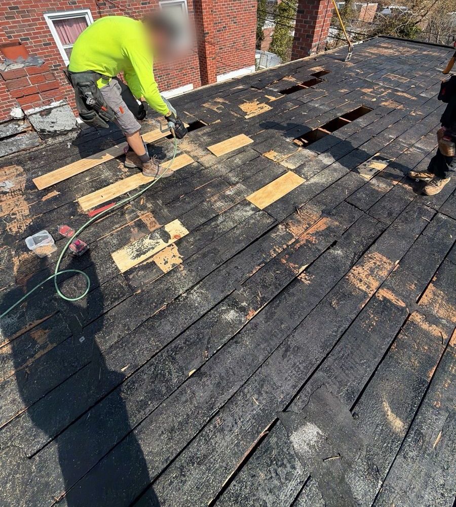 Roofer fitting new boards into an old plank roof deck in Roxborough, Philadelphia