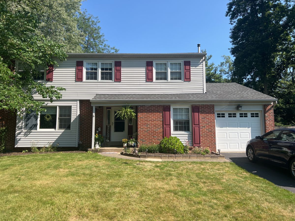 Two-story brick and light gray siding home in Morrisville before new siding