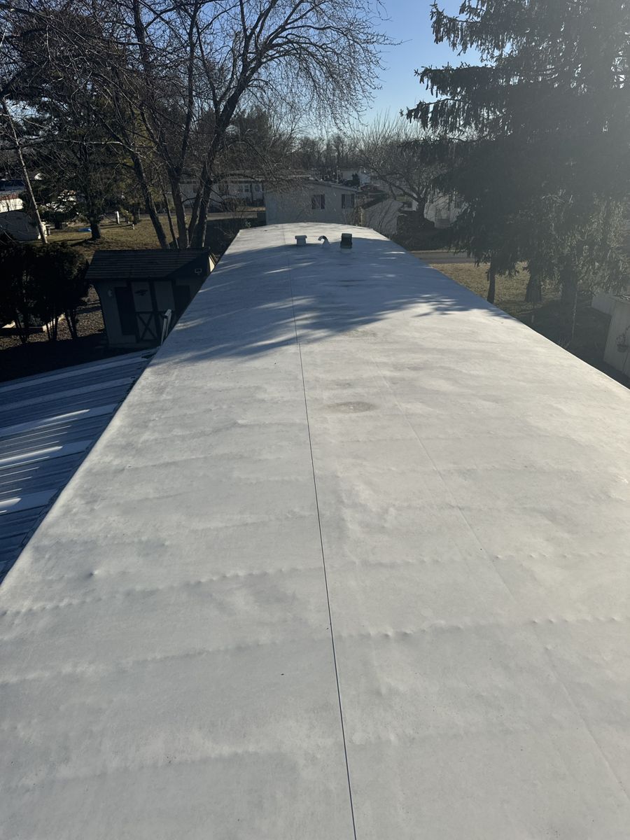 White-coated low-slope roof on a manufactured home in Morrisville before replacement