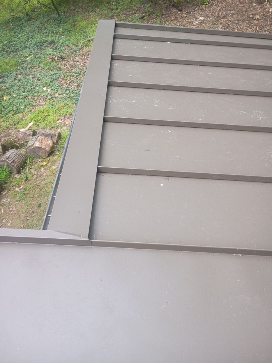Standing-seam metal panels and trim meeting a lower roof section