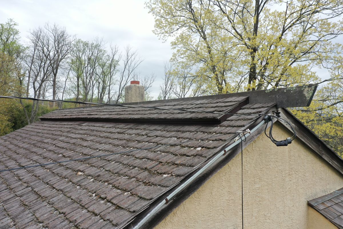 Weathered, moss-covered wood shake roof with a stepped ridge on a New Hope home