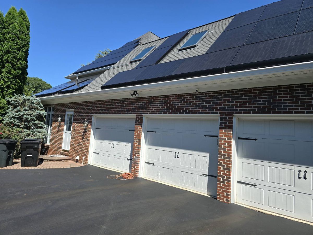New white seamless gutters along a brick garage with solar panels on the roof in Newtown
