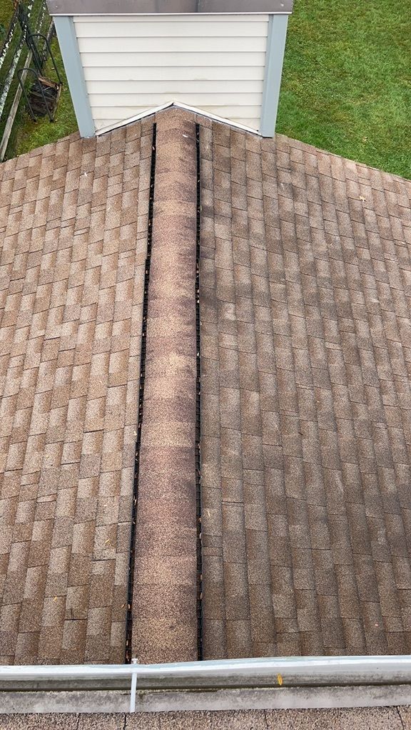 Worn brown asphalt shingles along the ridge of a Newtown roof before replacement