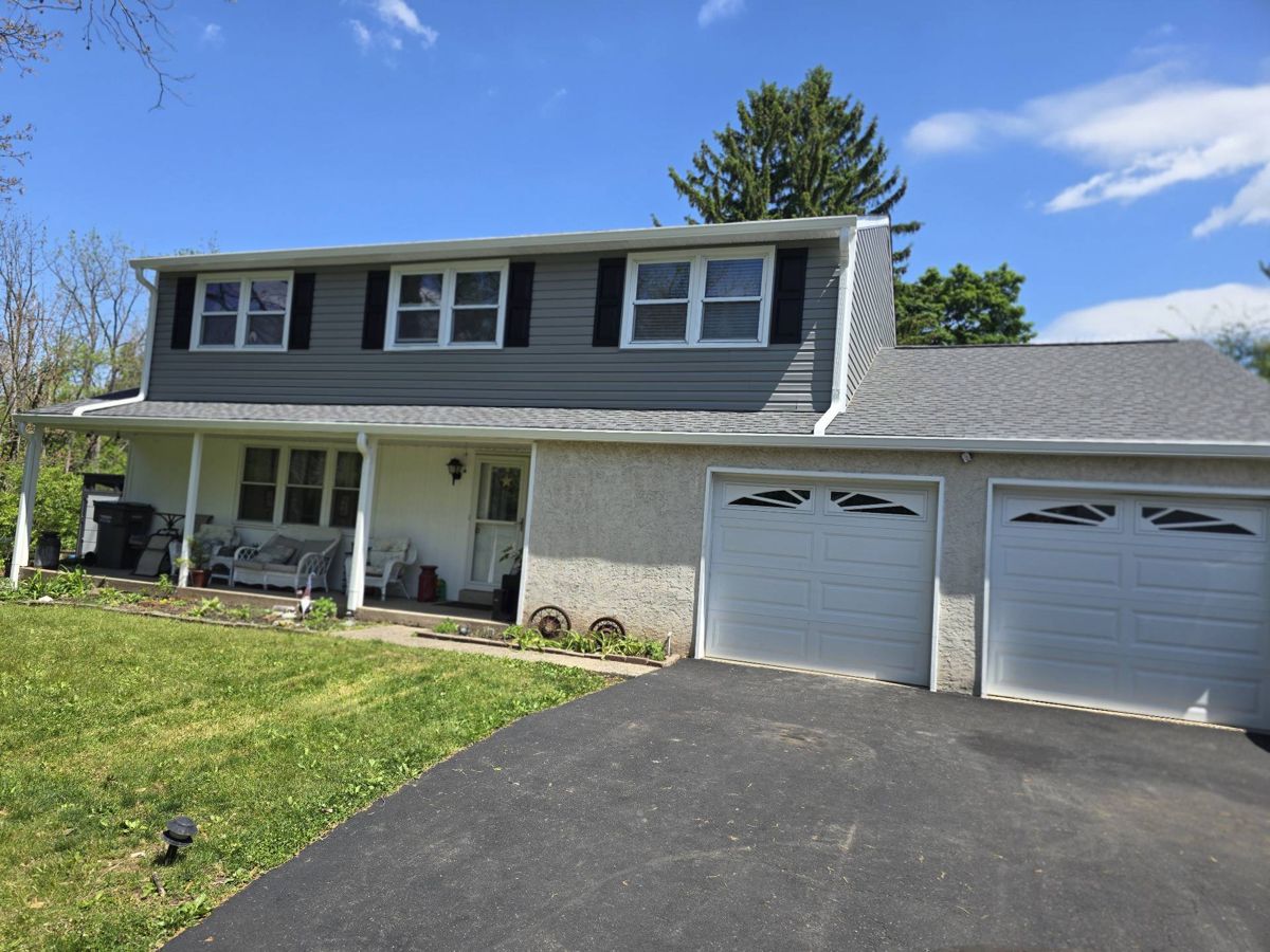 Two-story home in Lansdale, PA with a new roof and new gray siding on the upper story