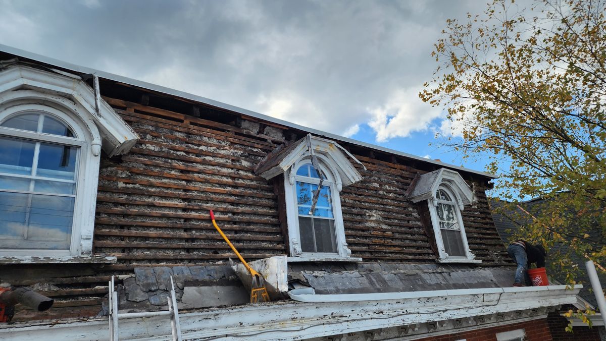 Mansard roof stripped to its board sheathing around arched dormers in North Wales, PA