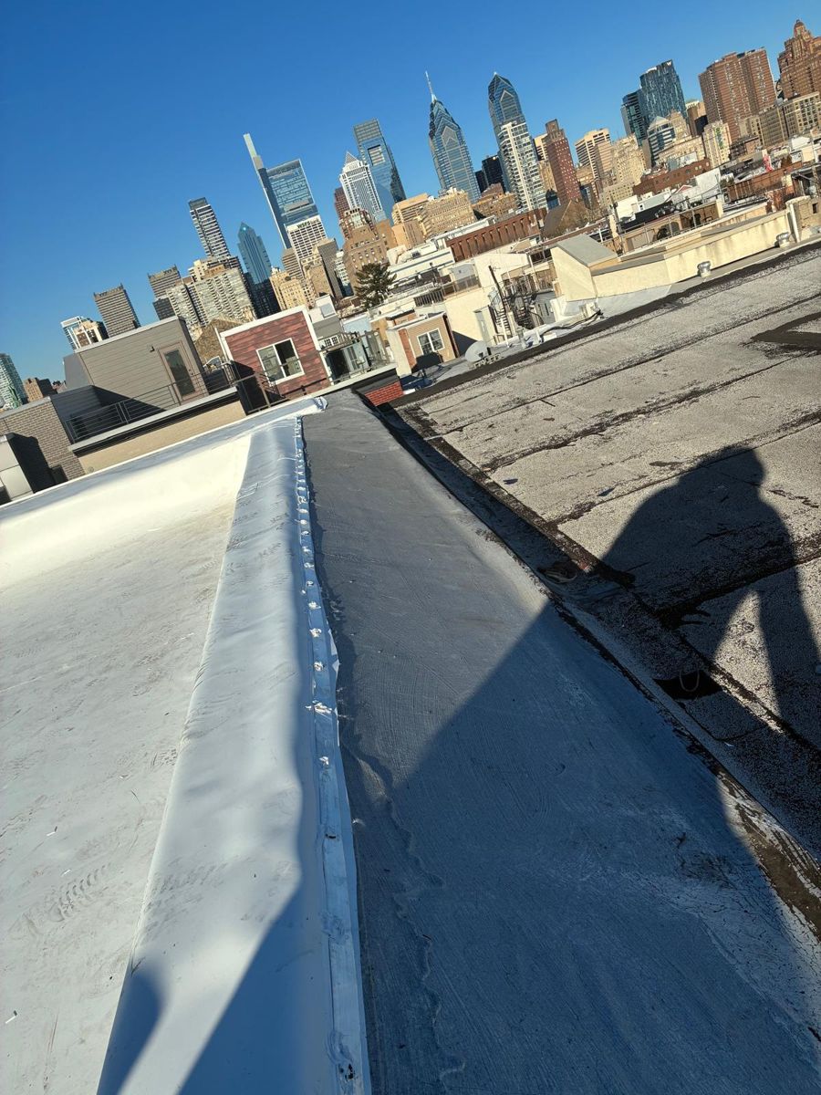 New white TPO membrane carried up a parapet wall with the Center City skyline behind