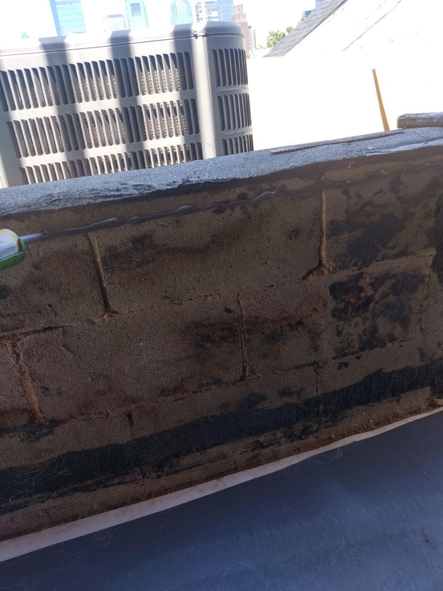 Deteriorated old roofing along a parapet wall on a Philadelphia rowhome