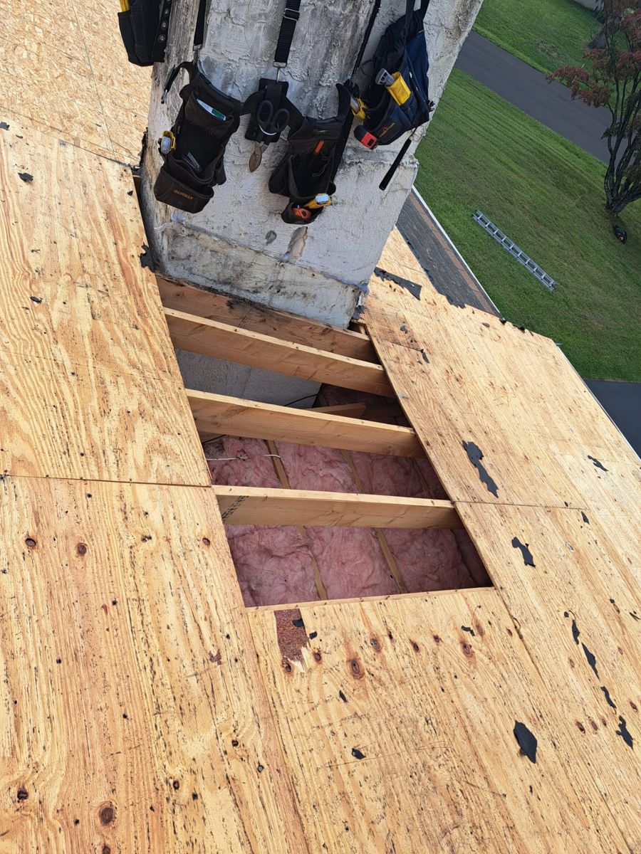 Roof deck opened to the rafters beside a chimney during a tear-off in Churchville, PA