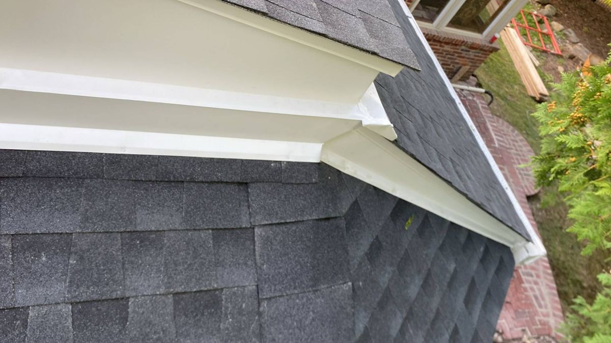 New dark gray shingles meeting the white trim at the end of a sunroom roof