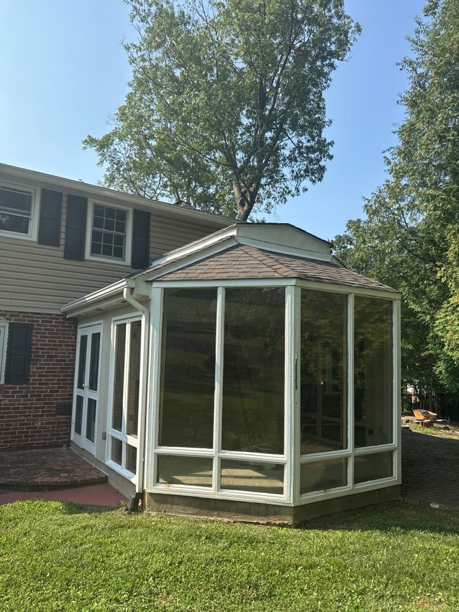 Sunroom with an aging brown shingle roof on the back of a Southampton building