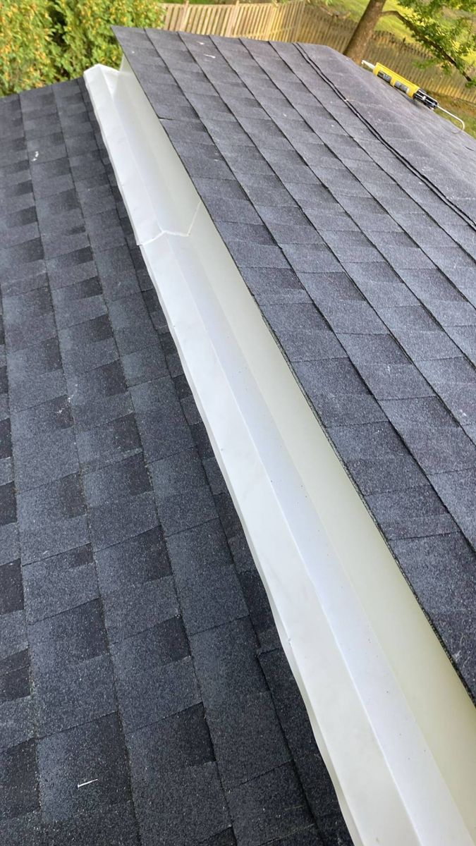 New dark gray shingles running along the white ridge trim of a sunroom roof