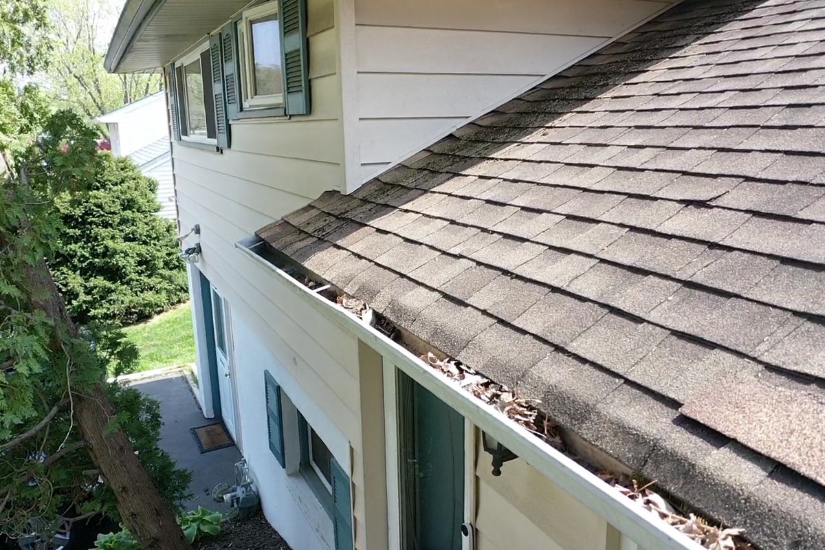 Old shingle roof with a gutter full of leaves and debris on a home in Abington, PA