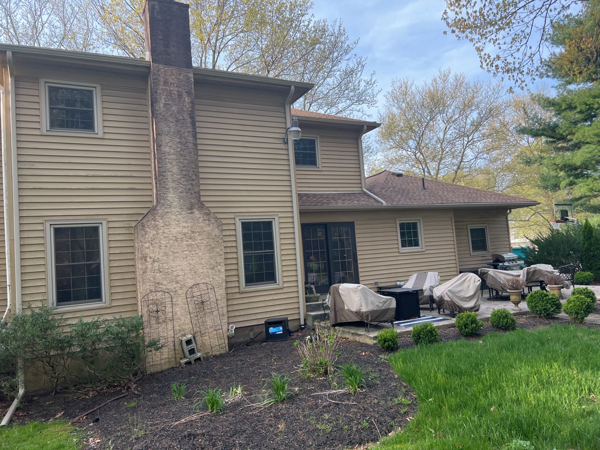 Weathered tan siding on the back of a Yardley home before replacement
