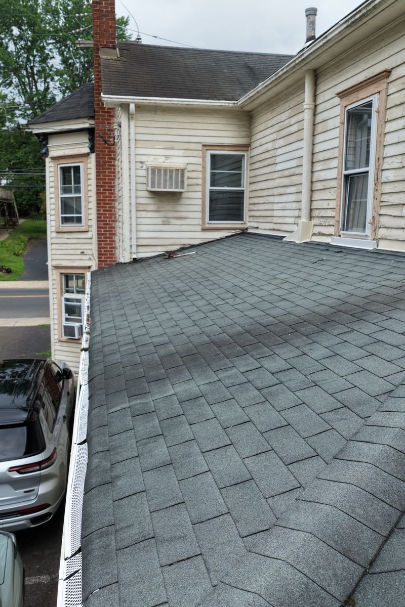 Worn three-tab shingles on the lower rear roof of an older clapboard building in Yardley
